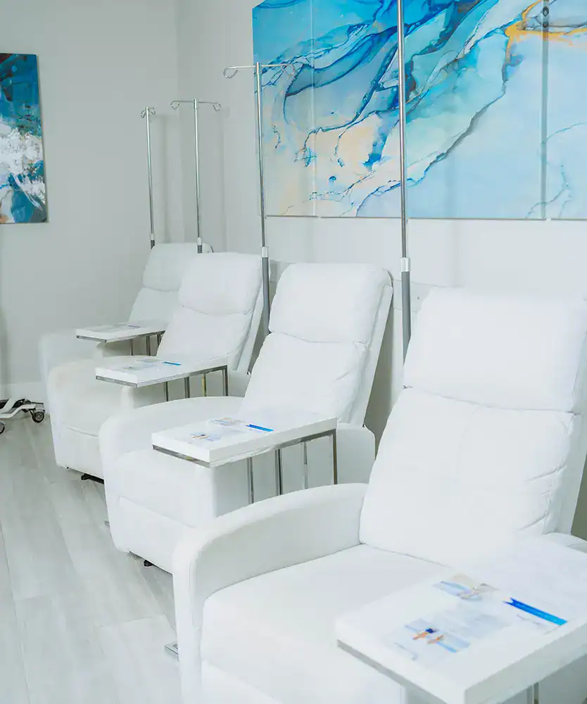 Modern medical spa treatment room with comfortable white infusion and recovery chairs.