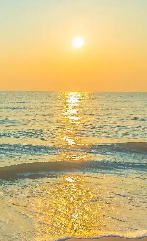 Ocean sunrise with gentle waves on the beach.