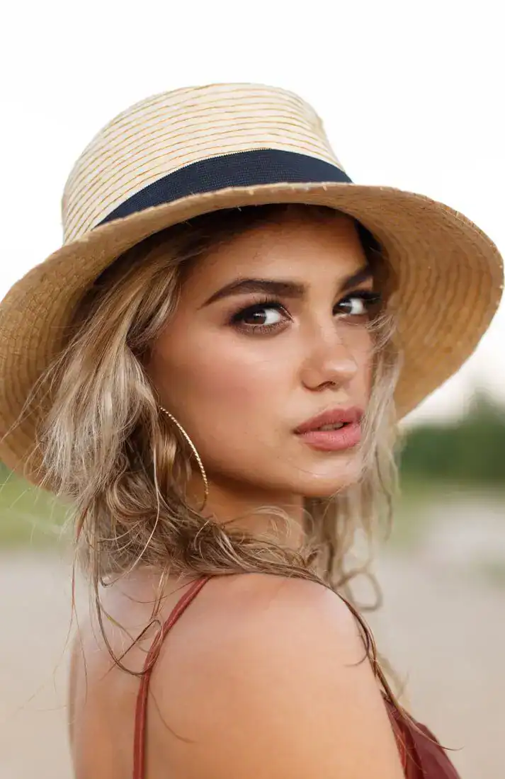 Woman wearing a straw hat with natural makeup and healthy, sun-kissed skin outdoors