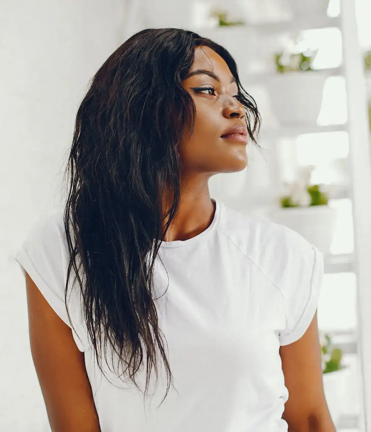 Woman with healthy, natural skin looking to the side in a bright, modern indoor space.