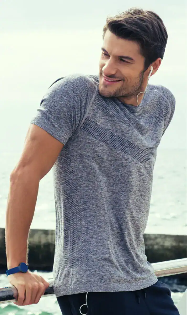 Active man in athletic wear listening to music while exercising outdoors by the water.