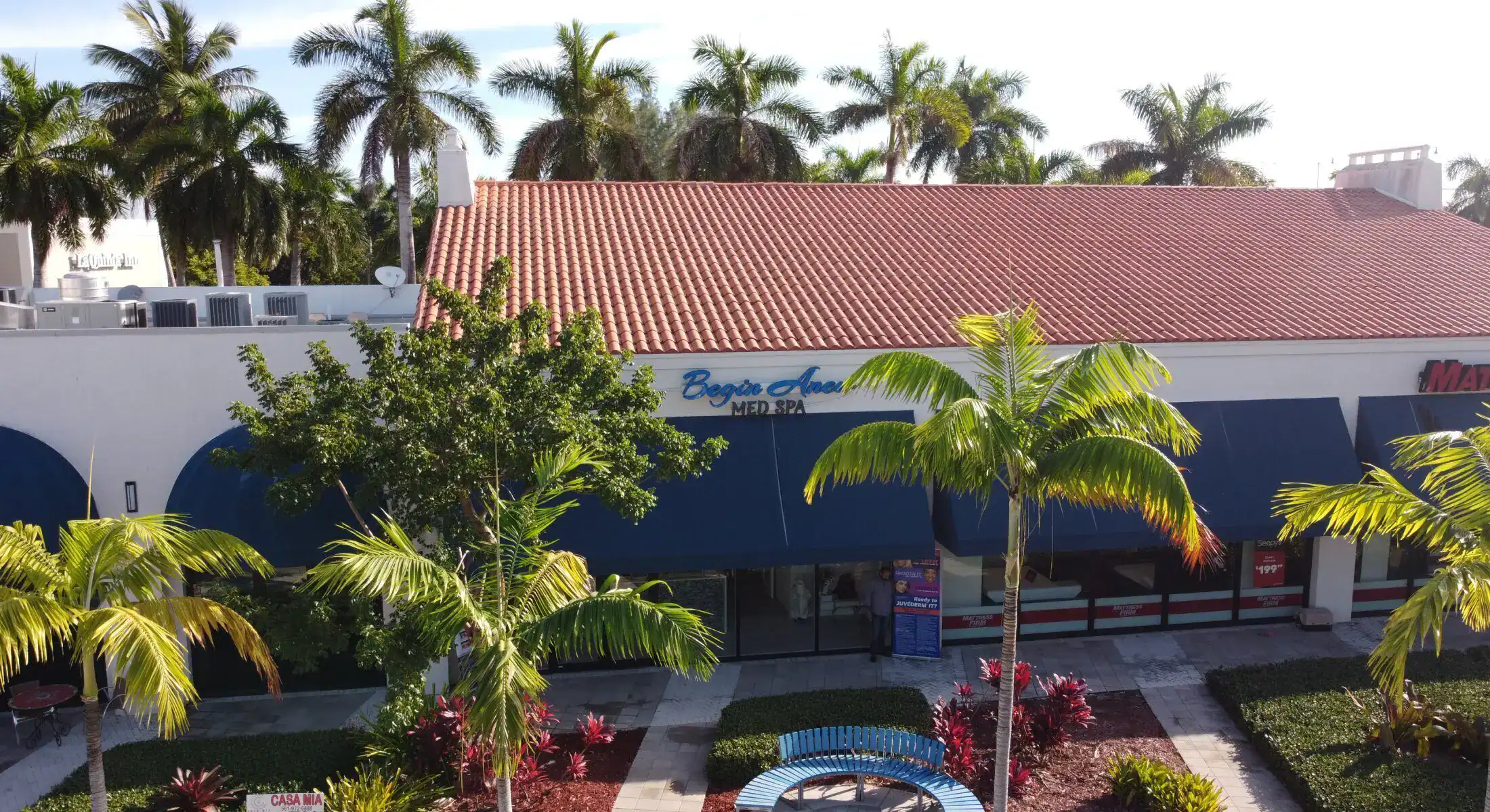 Exterior view of a medical spa building with palm trees and parking area.