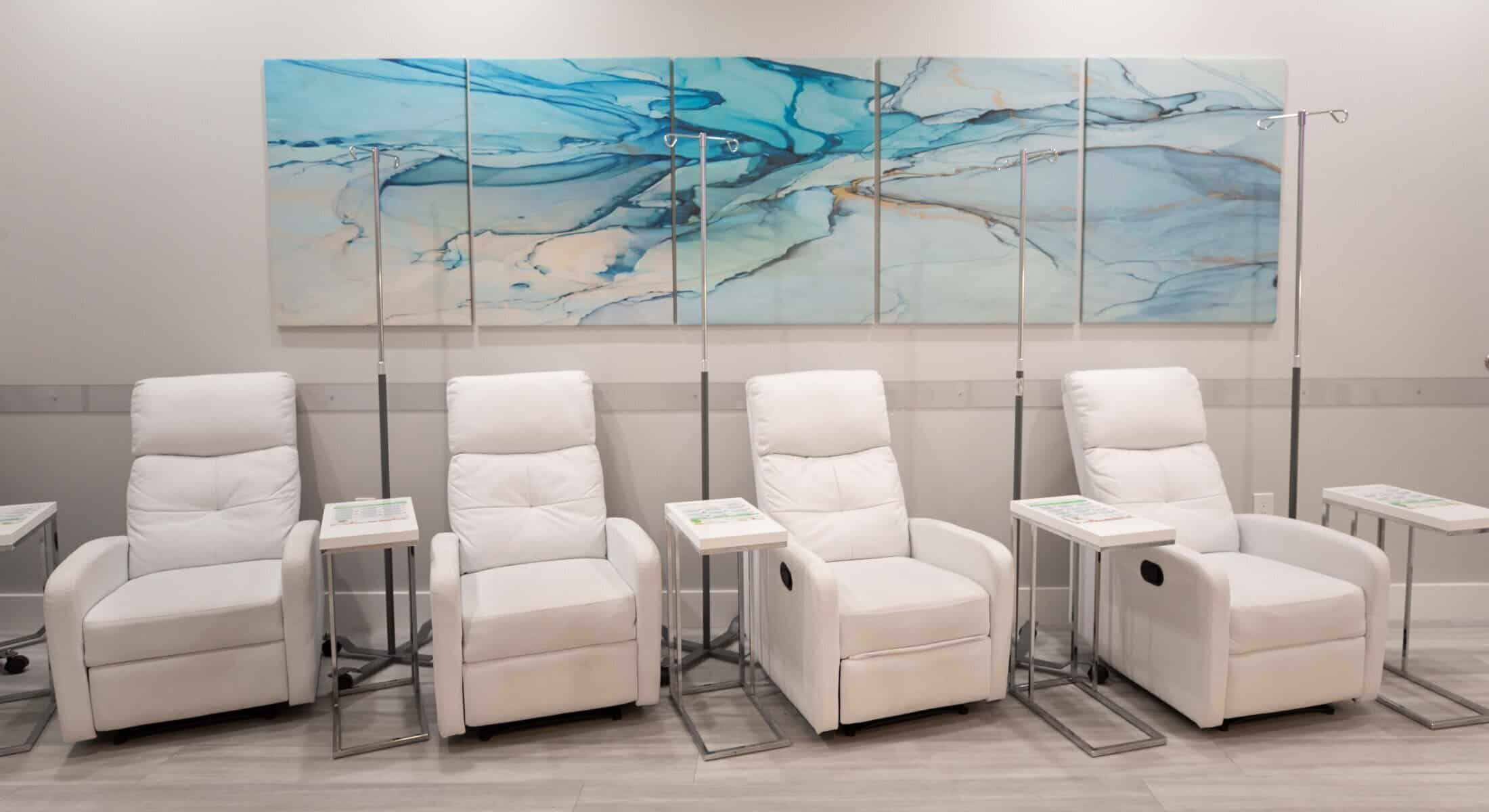 IV therapy lounge with white reclining chairs and infusion stands in a modern wellness clinic.