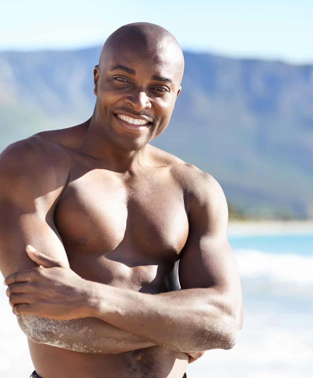 Fit man smiling at the beach representing healthy lifestyle