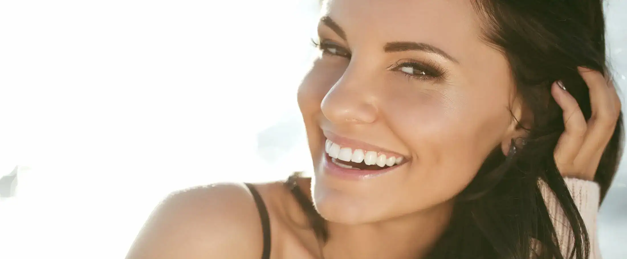 Portrait of a woman with long wet hair posing on a sandy beach.
