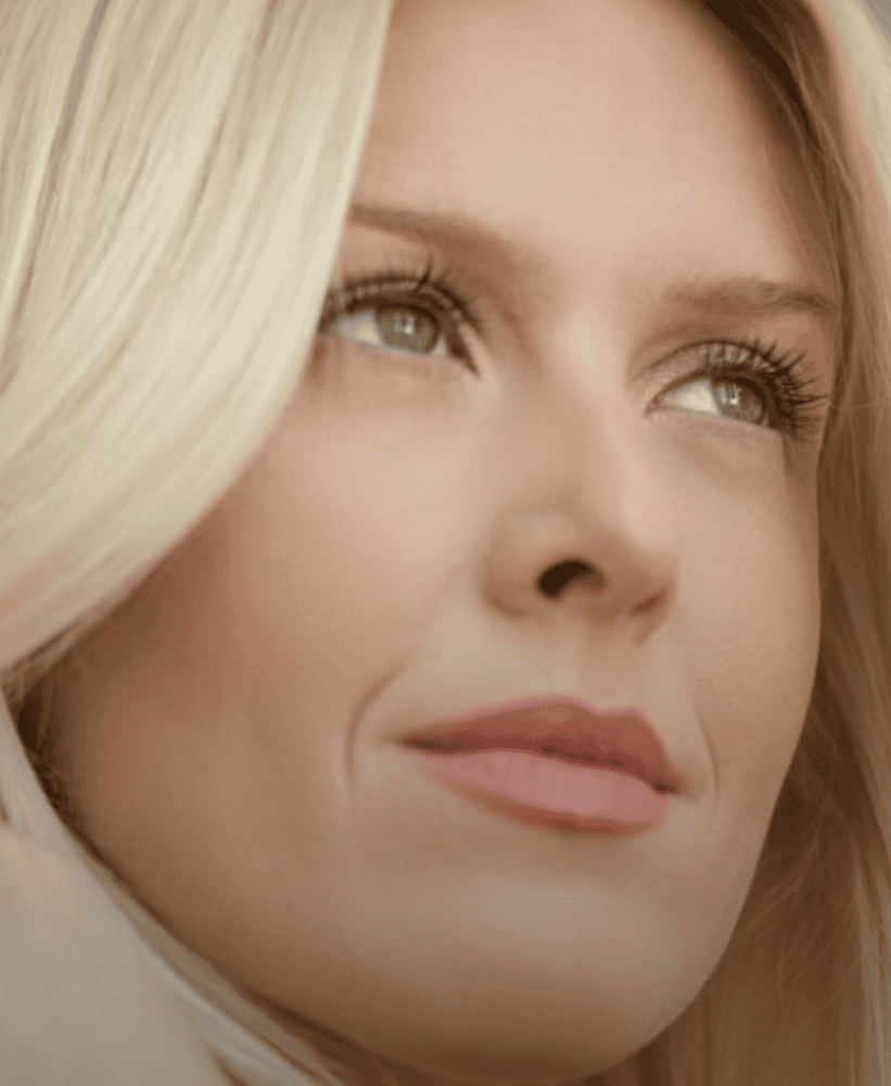 Woman looking slightly upward in a softly lit portrait.