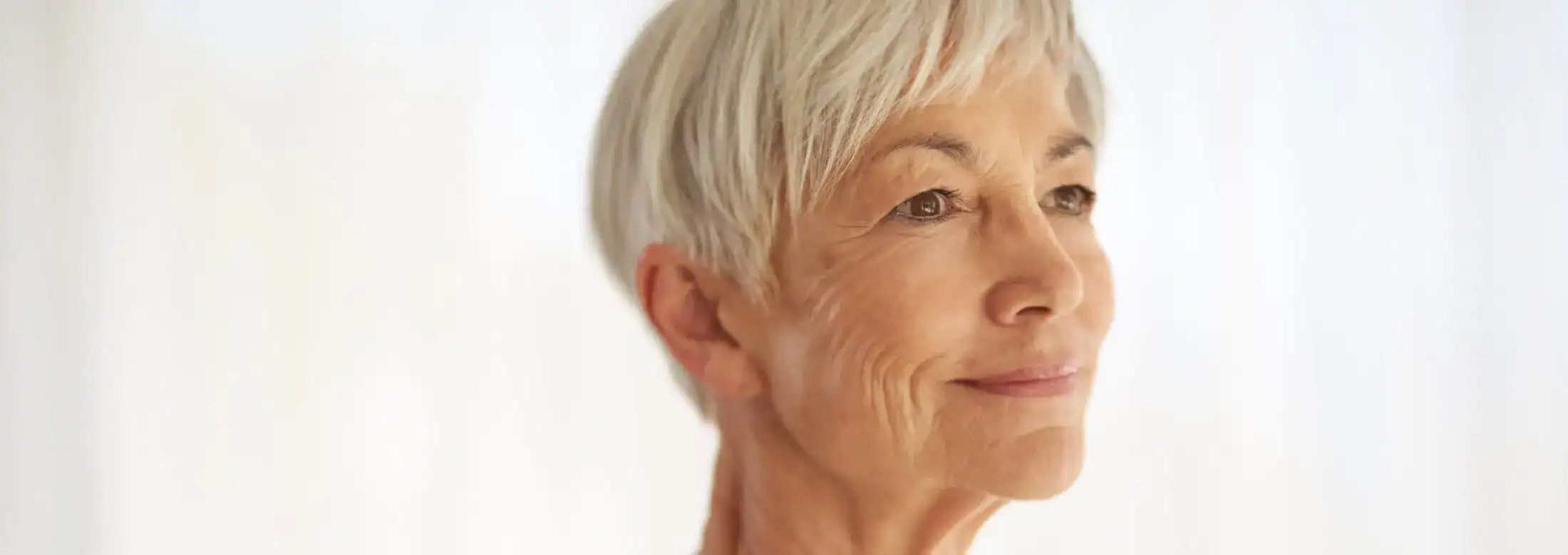 Smiling senior woman with clear skin after anti-aging treatment.