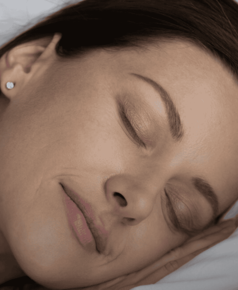 Close-up of a peaceful woman sleeping on a white pillow.