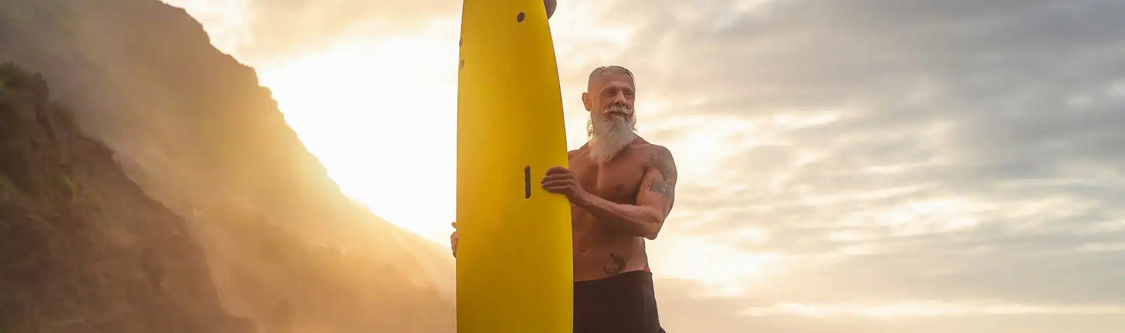 Active senior man with surfboard enjoying coastal lifestyle