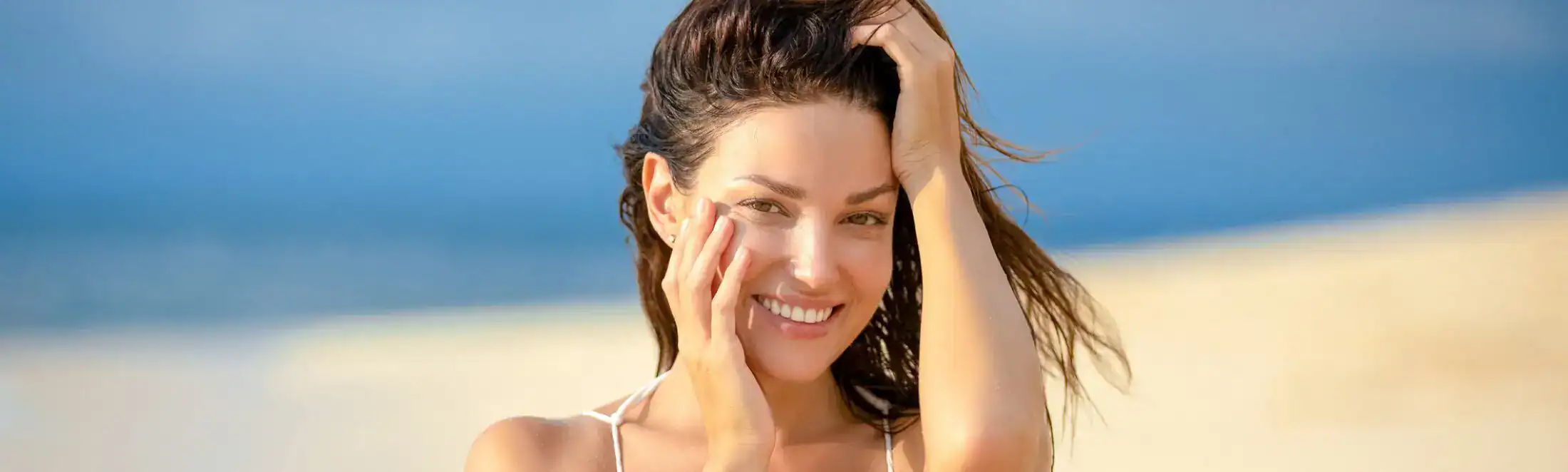 Smiling woman with natural glowing skin outdoors at the beach.