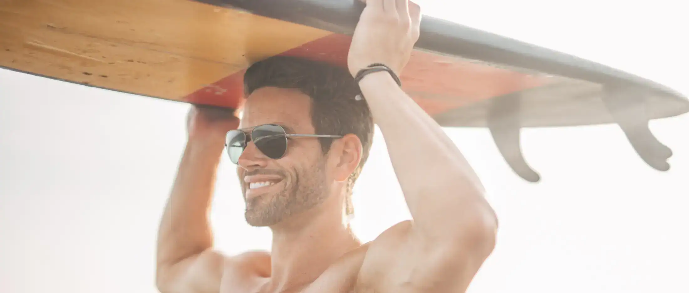 Active lifestyle man carrying surfboard at the beach
