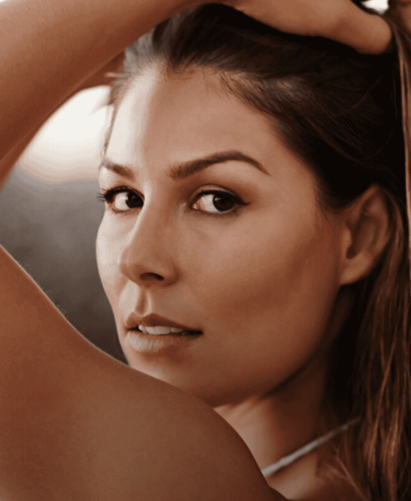 Close-up portrait of a woman with smooth, tanned skin and natural makeup.