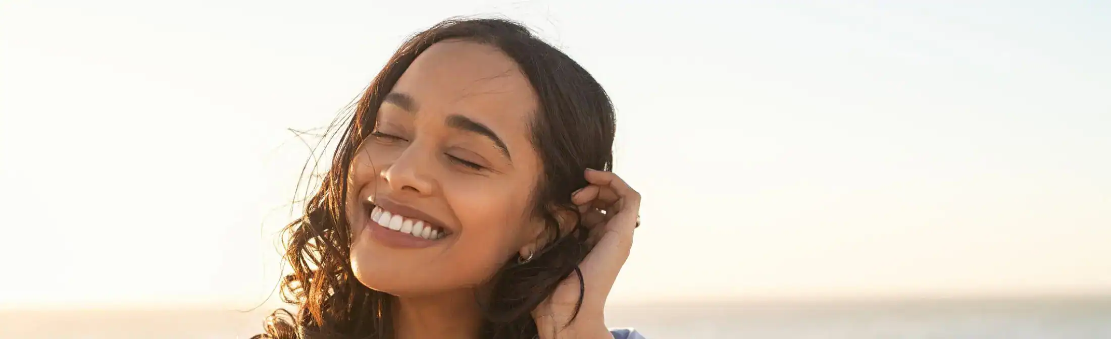 A woman with a glowing and clear complexion smiling outdoors, representing healthy skin results.