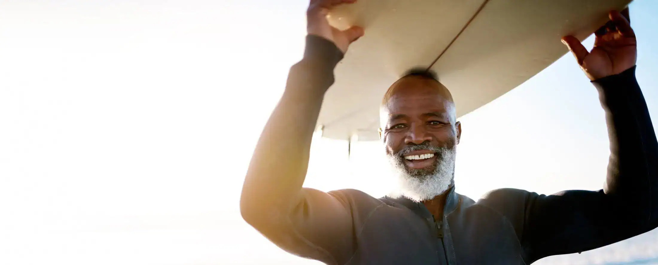 Active older man holding surfboard at the beach