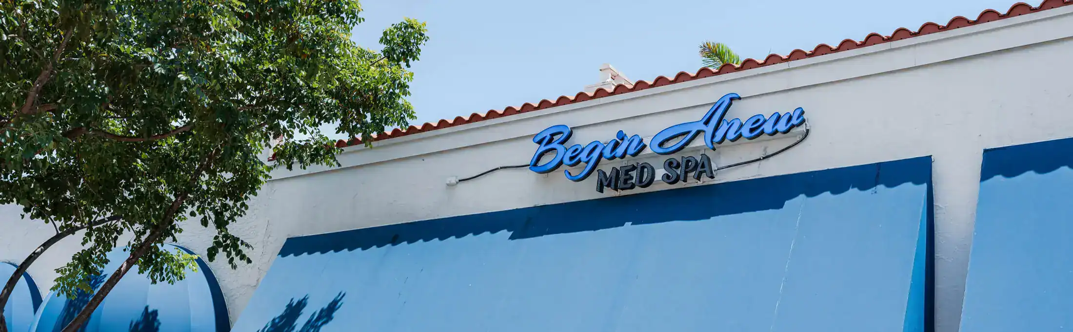 Exterior of Begin Anew Med Spa with storefront sign and blue awning.