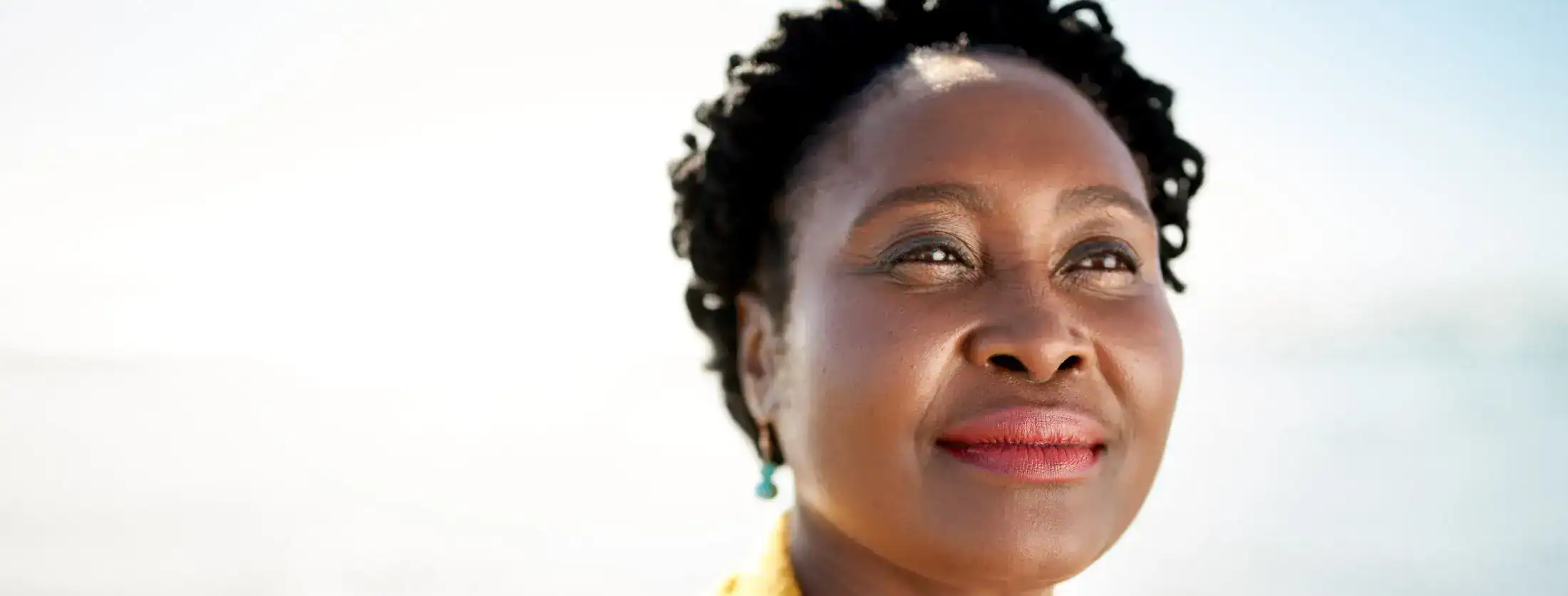 Close-up profile of a serene Black woman with a slight smile and turquoise earrings.