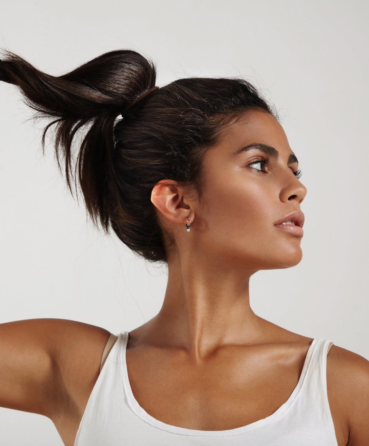 Woman with a high ponytail wearing a white tank top.