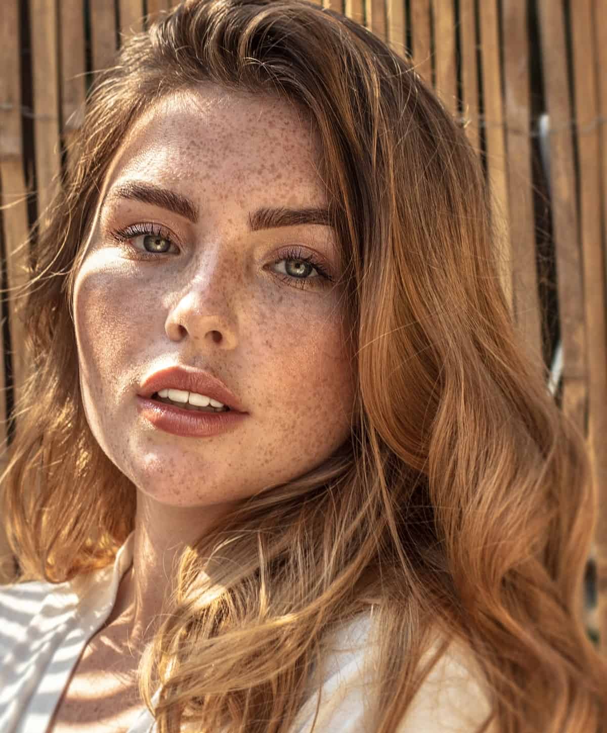 Portrait of a freckled woman with blonde hair in sunny outdoor lighting.