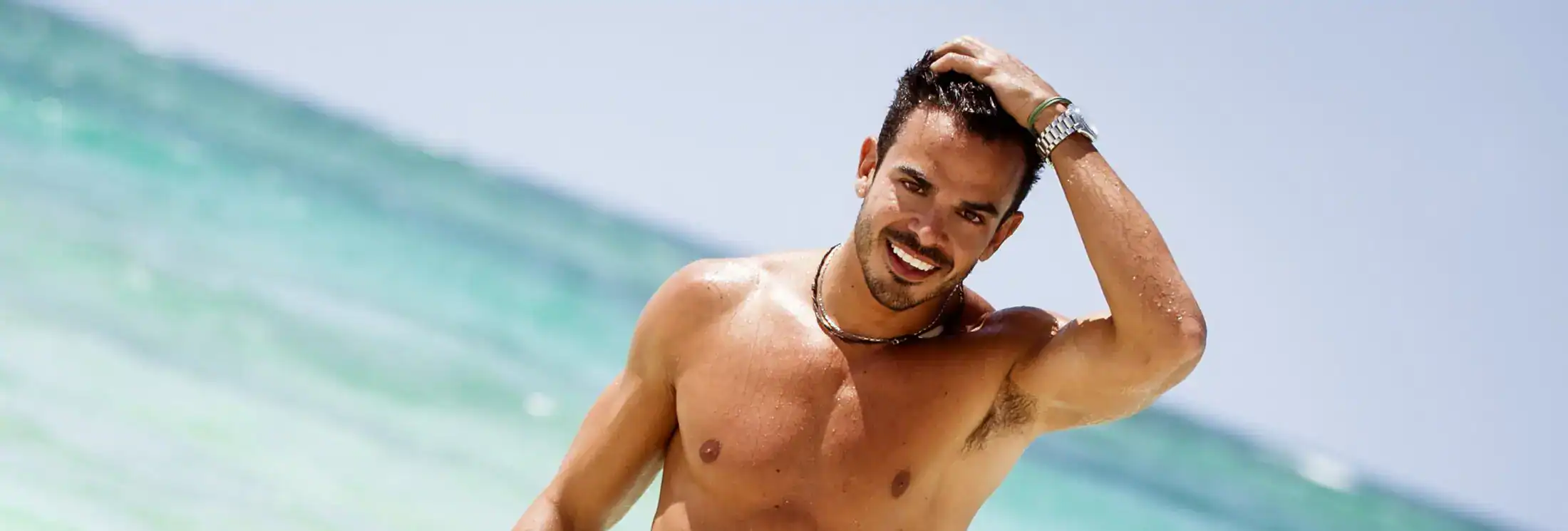 Smiling, fit man at beach representing energy and testosterone therapy results.