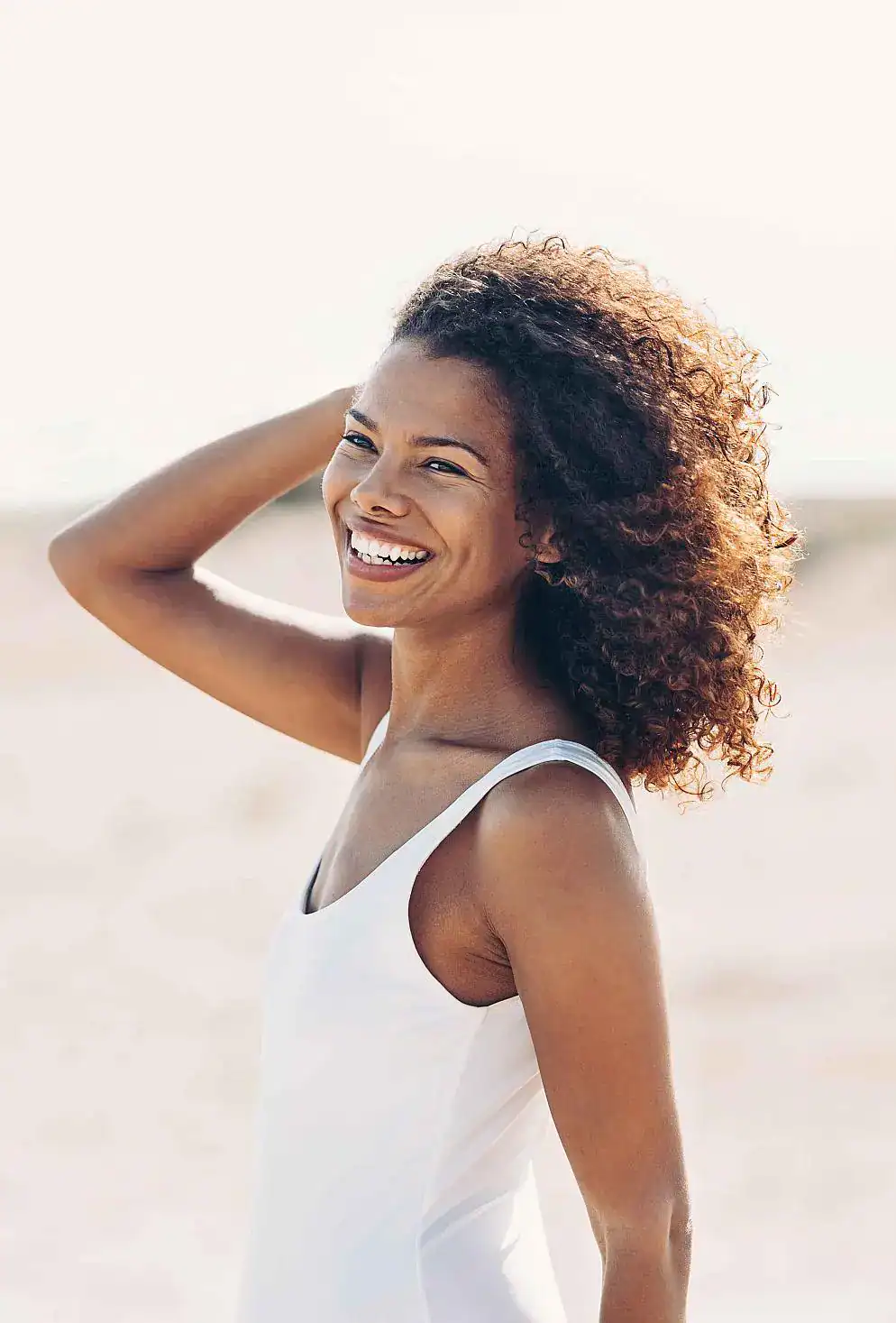 Smiling woman with healthy skin and hair representing wellness and vitality.