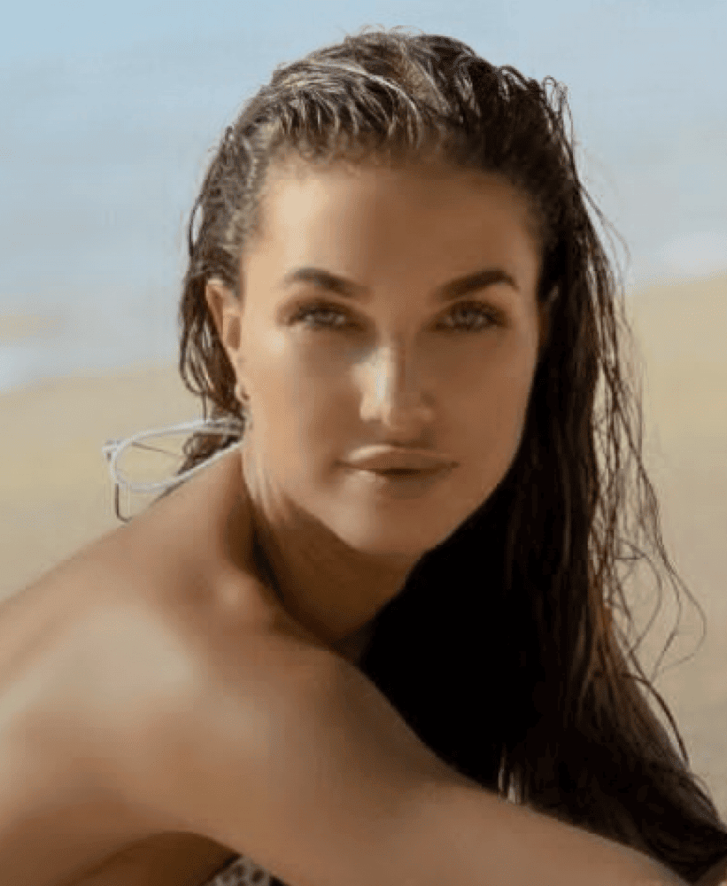 Portrait of a woman with wet hair posing on a sandy beach at sunset.