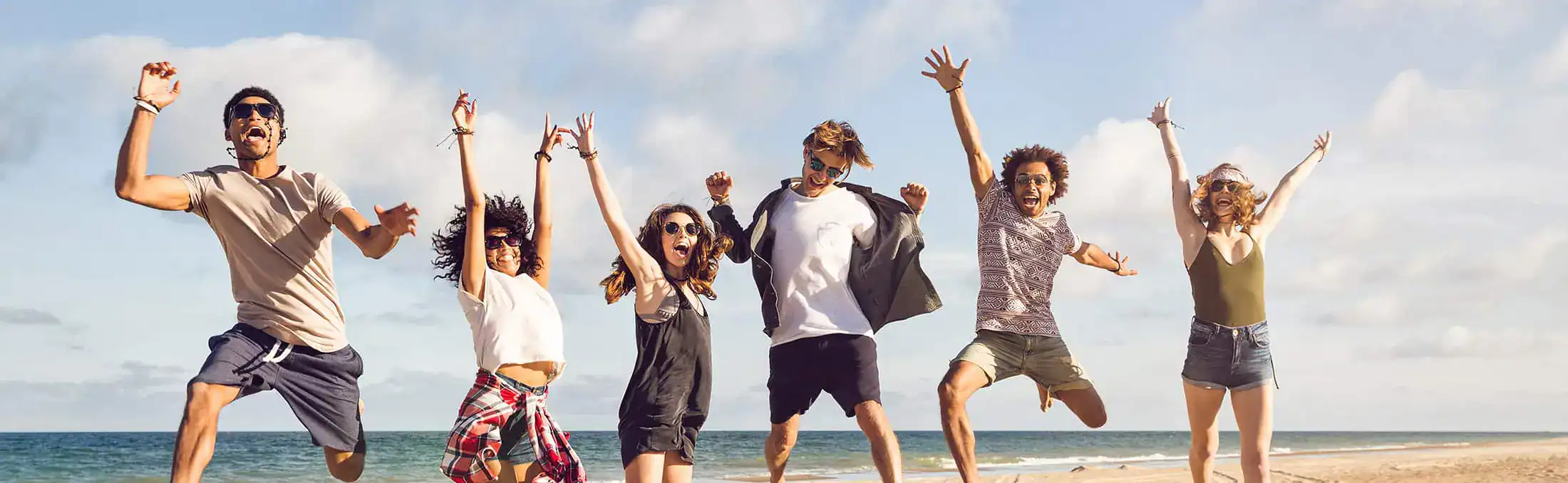Group of friends jumping together on a beach.