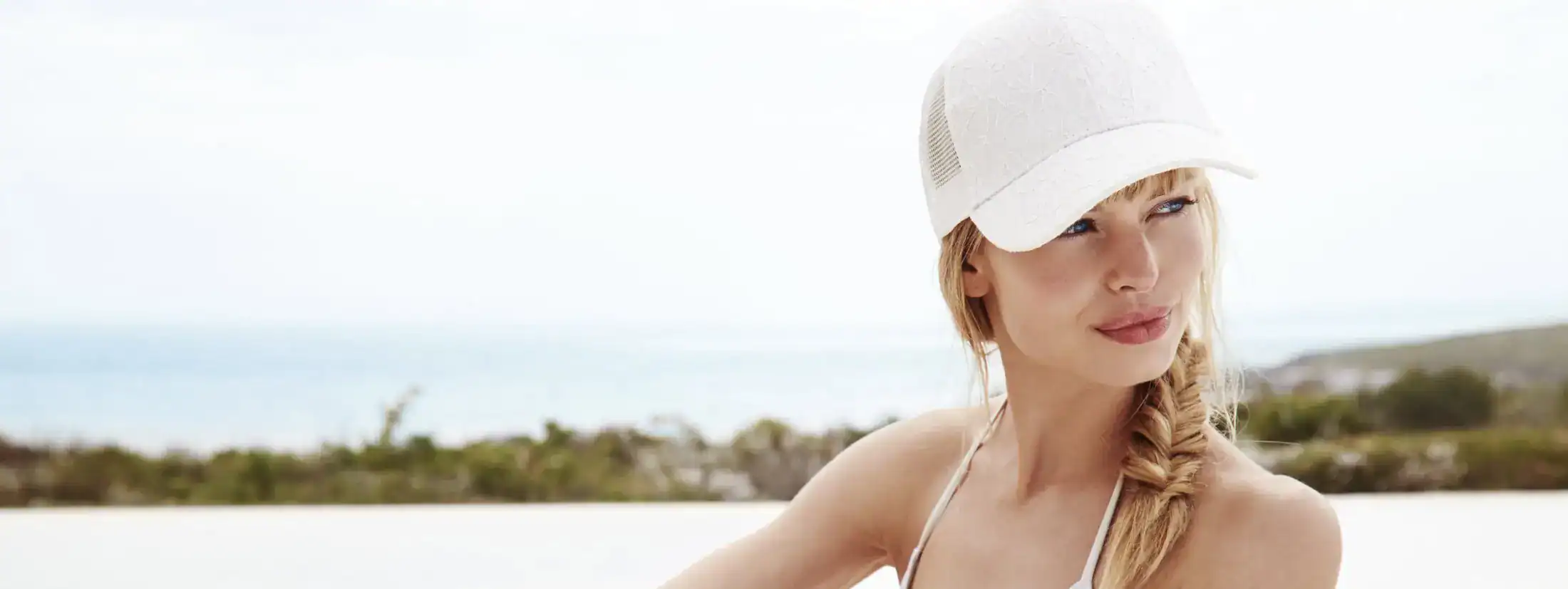 Healthy woman in white cap on beach representing skin protection and vitality.