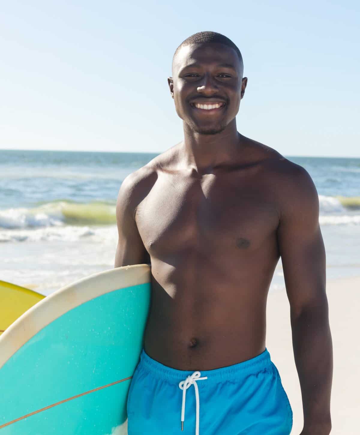 Fit man with surfboard illustrating healthy body composition and energy.