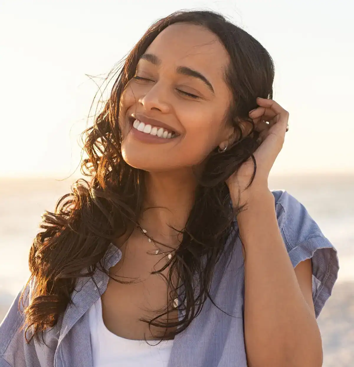 Close-up of a smiling woman with eyes closed enjoying natural sunlight.