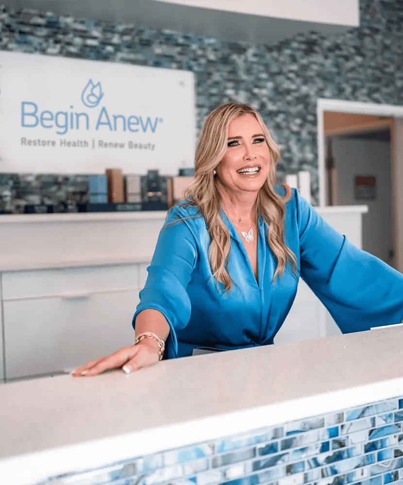 Friendly medical spa professional welcoming clients at the reception desk of Begin Anew.